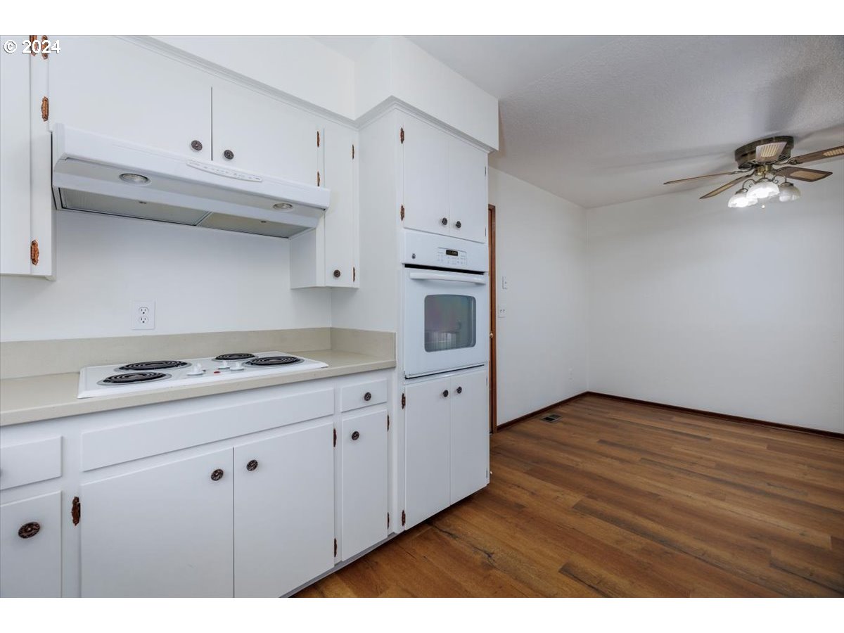 13400 Northwest Northrup Street Portland, OR 97229 - Photo 16 of 39 a kitchen with granite countertop a stove a sink and white cabinets with wooden floor
