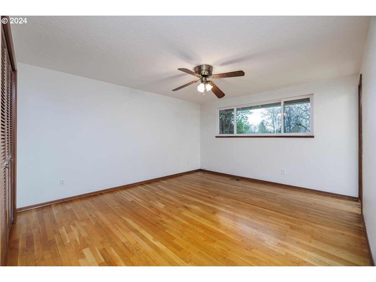 13400 Northwest Northrup Street Portland, OR 97229 - Photo 17 of 39 an empty room with wooden floor and chandelier fan