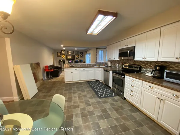 a kitchen with stainless steel appliances granite countertop a sink a stove top oven a dining table and chairs with wooden floor