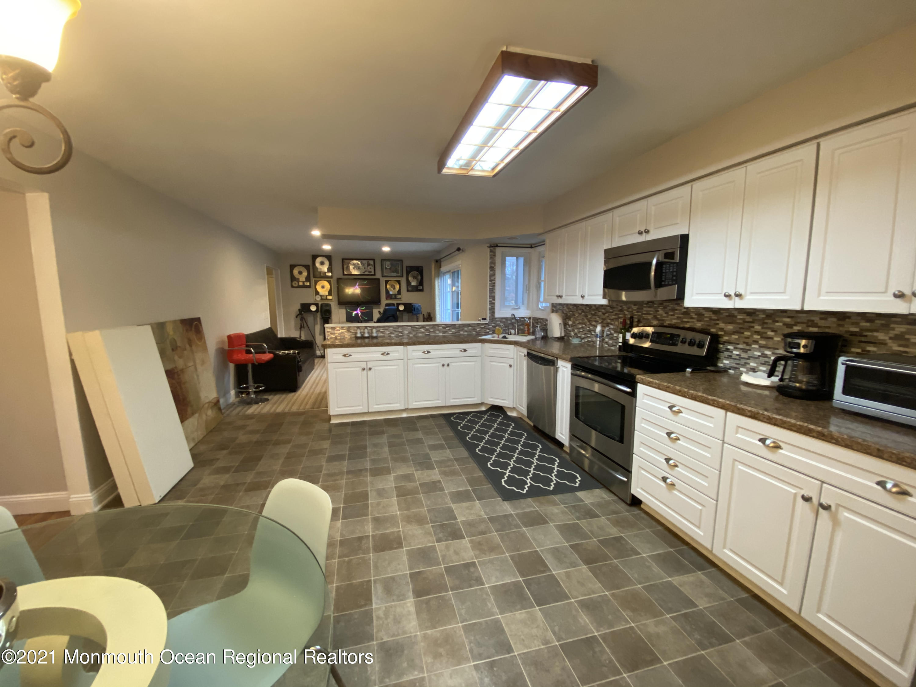 1304 Franklin Avenue Asbury Park, NJ 07712 - Photo 6 of 25 a kitchen with stainless steel appliances granite countertop a sink a stove top oven a dining table and chairs with wooden floor