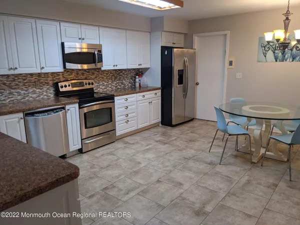 a kitchen with stainless steel appliances granite countertop a stove a sink a microwave a refrigerator and cabinets