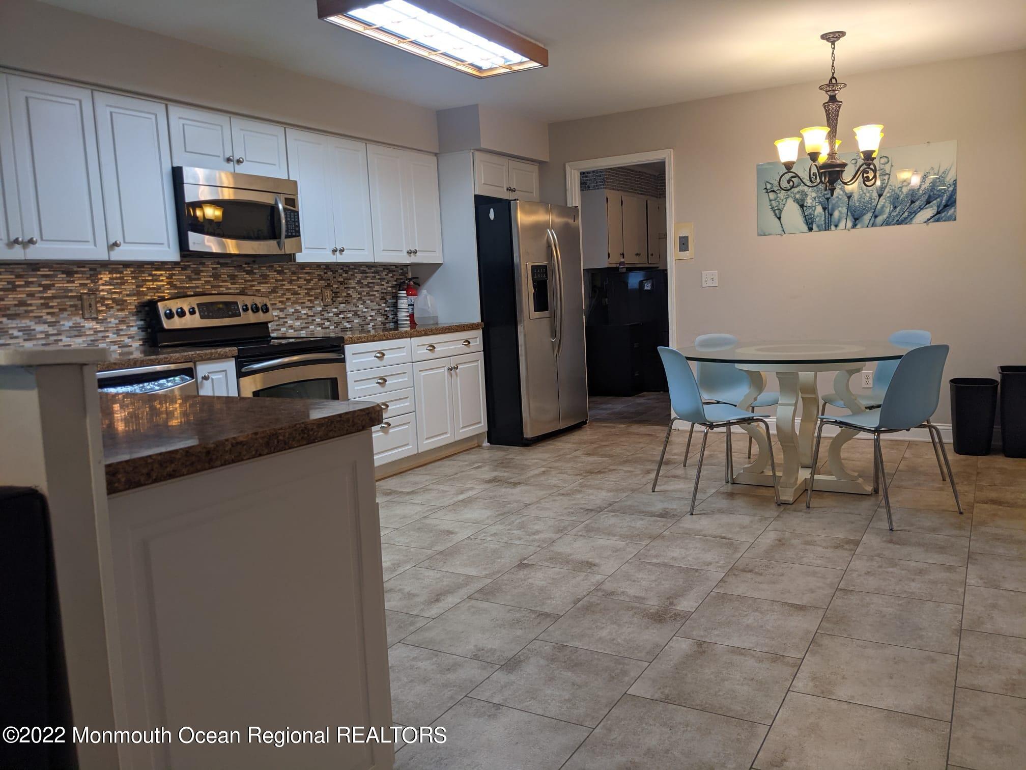 1304 Franklin Avenue Asbury Park, NJ 07712 - Photo 9 of 25 a kitchen with stainless steel appliances granite countertop a stove a refrigerator a microwave a sink a dining table and chairs