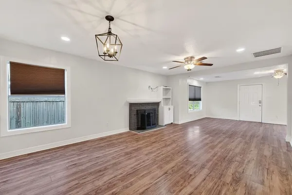 a view of an empty room with a window and wooden floor