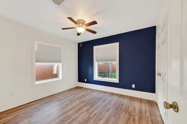a view of an empty room with a window and wooden floor