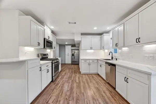 a kitchen with granite countertop a sink cabinets stainless steel appliances and a counter space