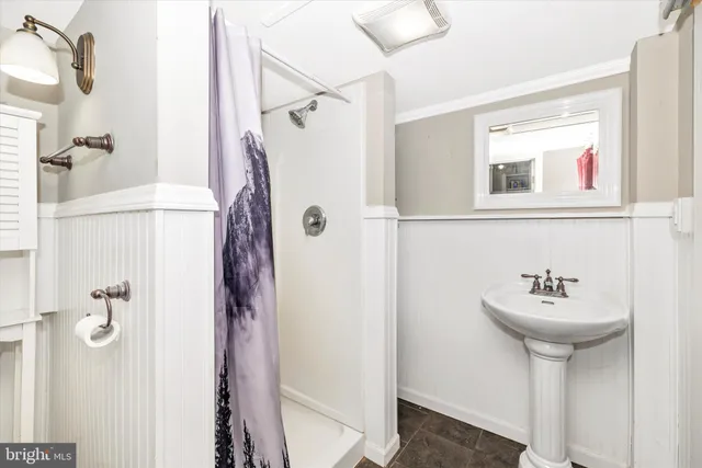 a bathroom with a sink a mirror a glass door a shower and vanity