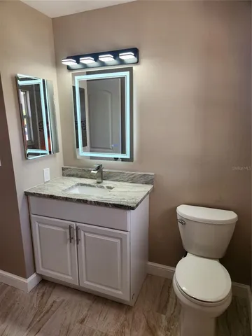a bathroom with a granite countertop toilet a mirror and a sink
