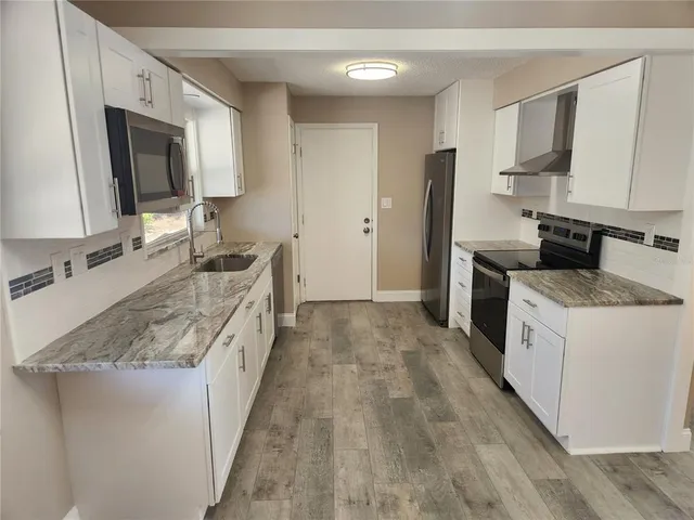 a large kitchen with a stove top oven a sink a refrigerator and microwave