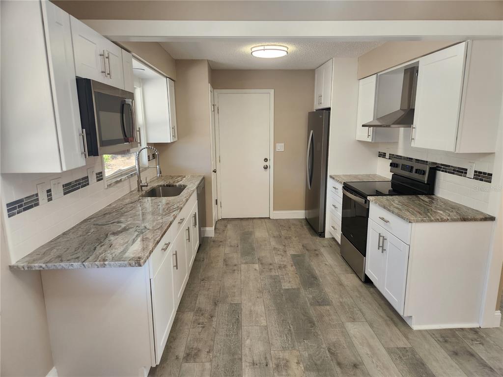 4462 Cynthia Lane Spring Hill, FL 34606 - Photo 2 of 22 a large kitchen with a stove top oven a sink a refrigerator and microwave