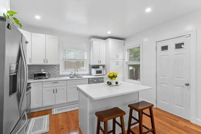 a kitchen with a sink a refrigerator and white cabinets