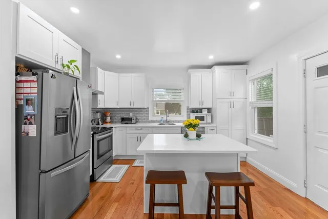 a kitchen with granite countertop a refrigerator a sink a stove a dining table and chairs