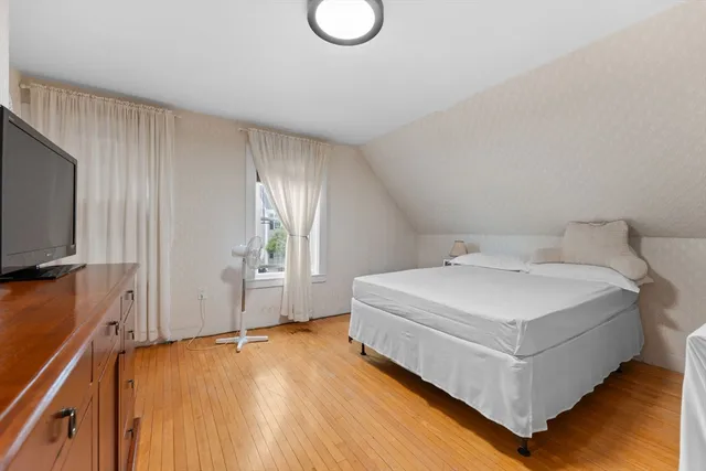 a white bed sitting in a room next to a window