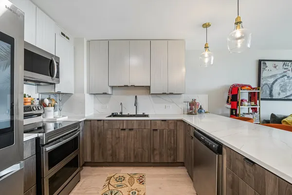 a kitchen with stainless steel appliances a sink dishwasher a stove top oven a refrigerator and cabinets with wooden floor