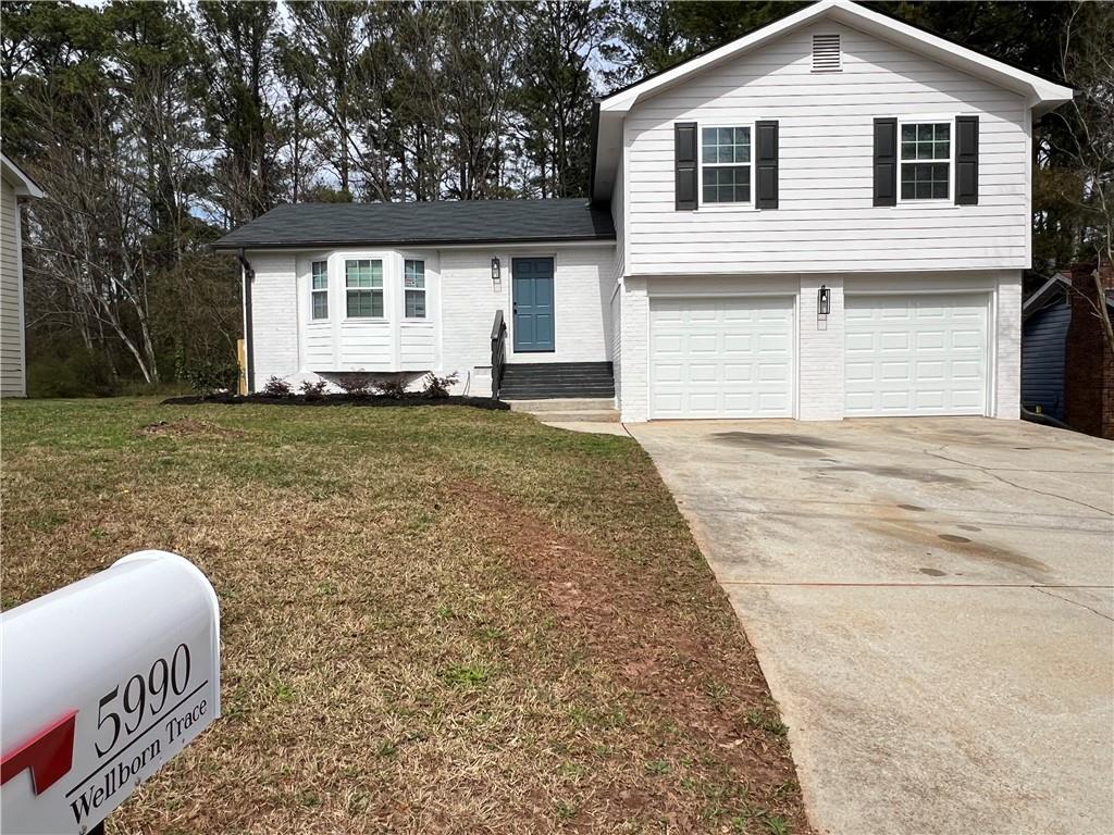 5990 Wellborn Trace Lithonia, GA 30058 - Photo 54 of 56 a front view of a house with a yard and garage