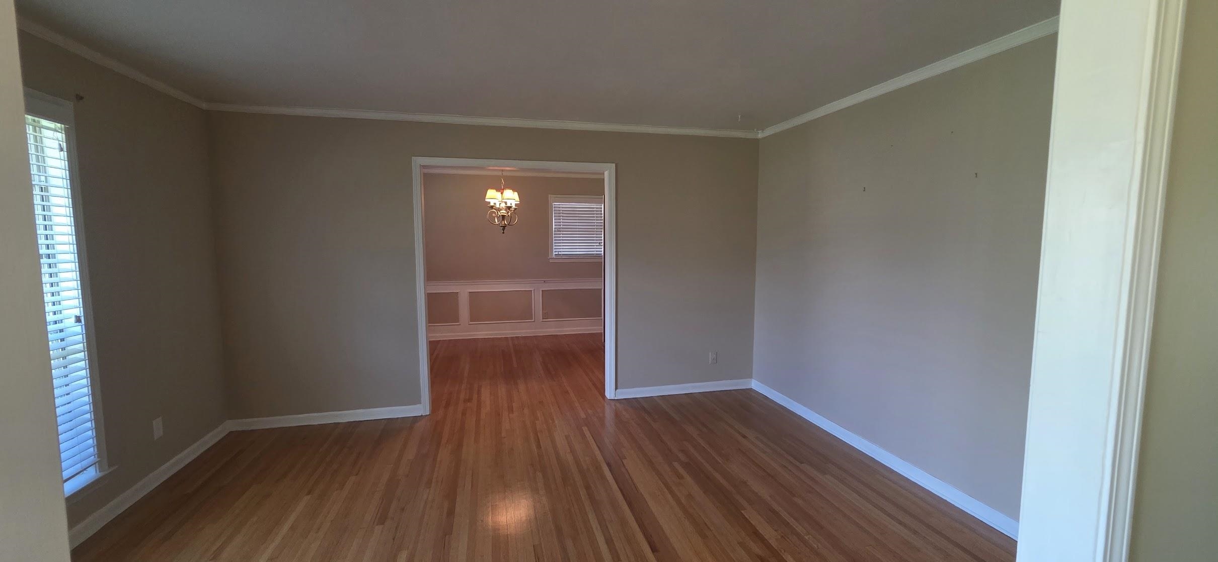 523 Shofner Avenue Memphis, TN 38109 - Photo 2 of 12 Empty room with dark wood-style flooring, ornamental molding, and a chandelier