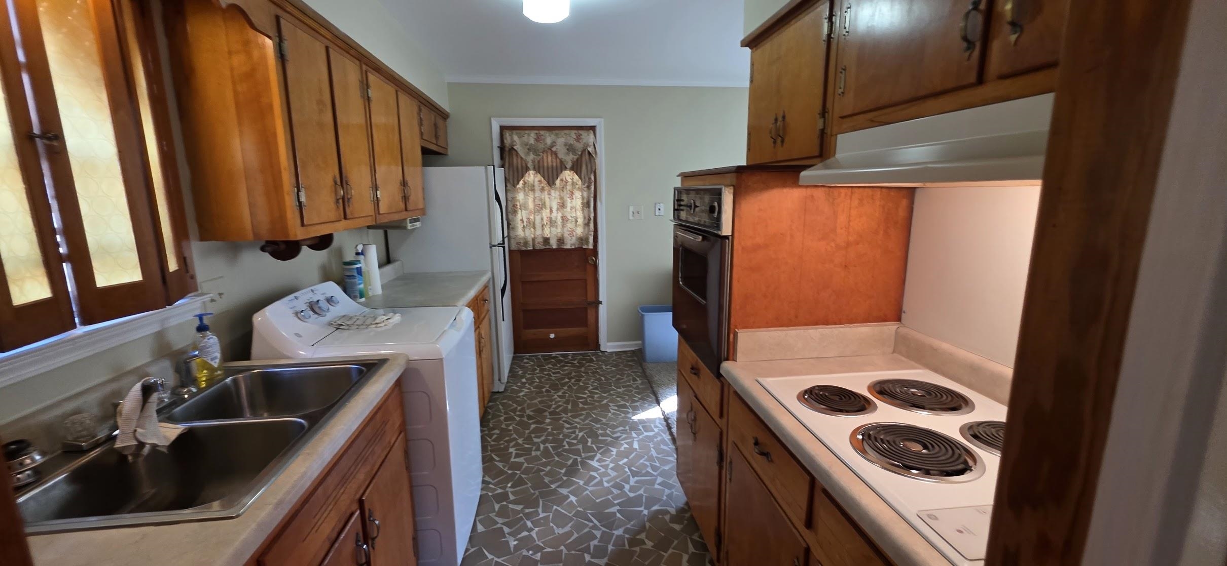 523 Shofner Avenue Memphis, TN 38109 - Photo 4 of 12 Kitchen with white appliances, light countertops, brown cabinetry, under cabinet range hood, and crown molding