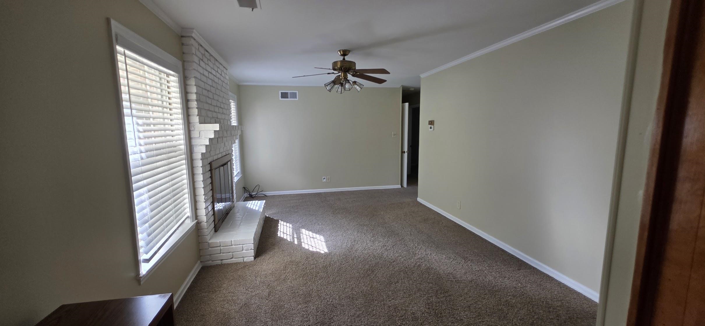 523 Shofner Avenue Memphis, TN 38109 - Photo 6 of 12 Unfurnished living room with carpet floors, crown molding, a fireplace, and ceiling fan