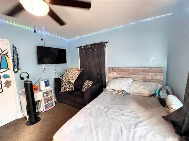 a bedroom with a bed a flat screen tv and a chandelier