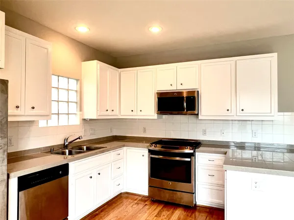 a kitchen with granite countertop white cabinets and white appliances