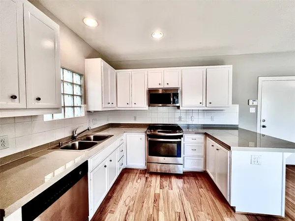 a kitchen with stainless steel appliances granite countertop white cabinets sink stove and microwave