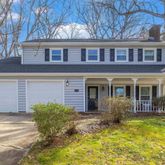 a view of house with yard and large tree in front