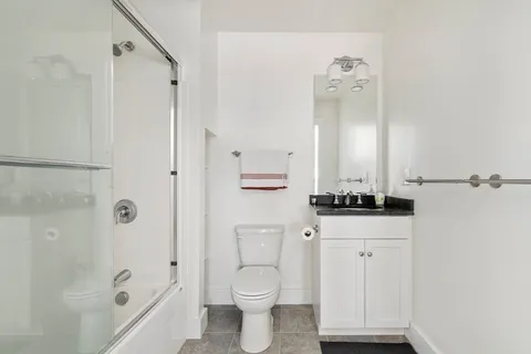 a bathroom with a granite countertop sink a toilet and shower