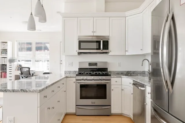 a kitchen with granite countertop white cabinets and stainless steel appliances