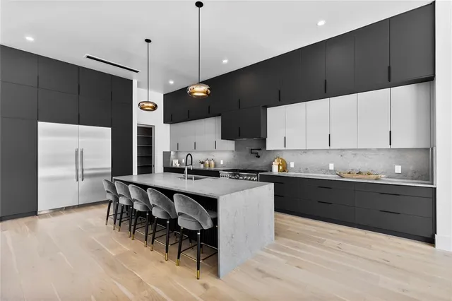 a large kitchen with stainless steel appliances kitchen island a large counter top a stove and a wooden floors