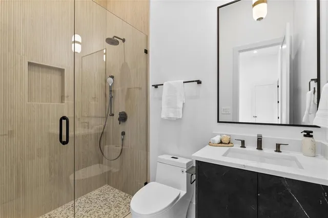 a bathroom with a sink vanity granite toilet and shower