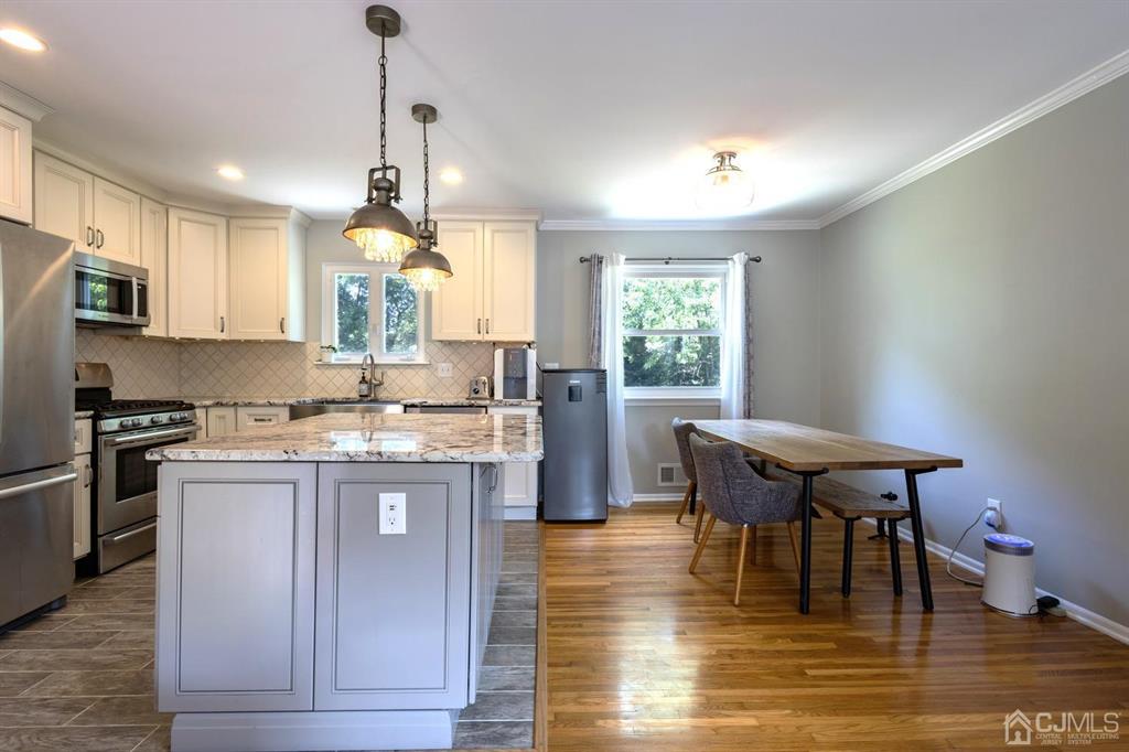 53 Edgemere Avenue Plainsboro, NJ 08536 - Photo 7 of 39 a kitchen with stainless steel appliances granite countertop a stove top oven a refrigerator a dining table and chairs with wooden floor