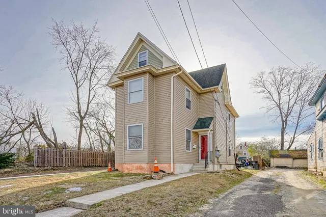 a front view of a house with large trees