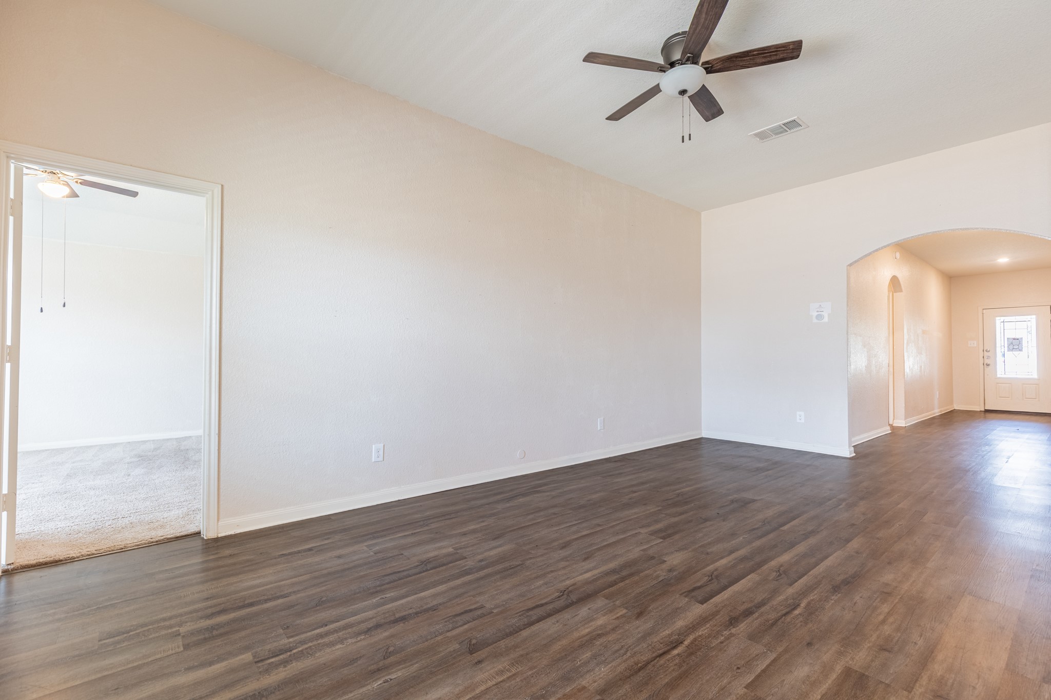 20017 Hubert R Humphrey Road Manor, TX 78653 - Photo 13 of 35 Rich wood-look flooring and an arched entryway define this inviting common area.