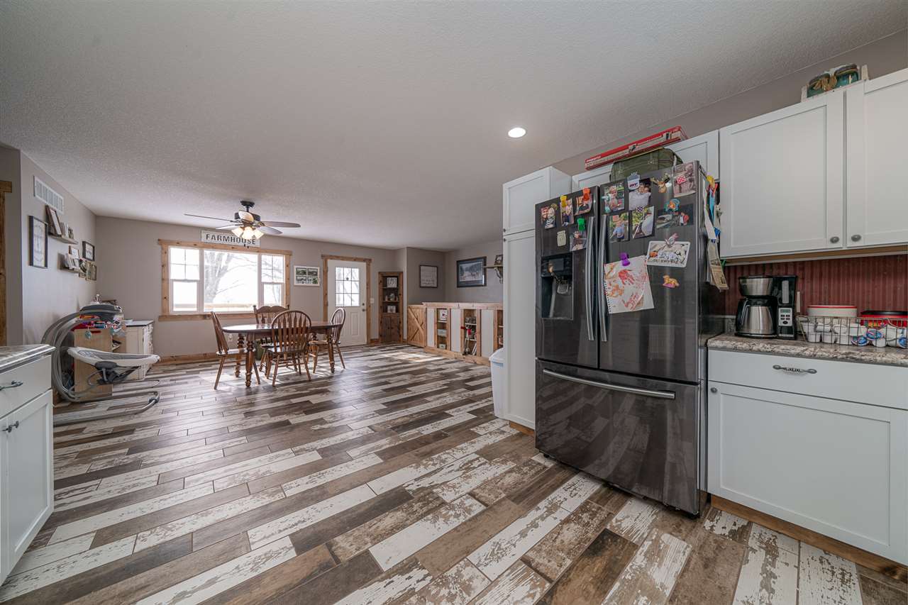 1785 Willow Road Franklin Grove, IL 61031 - Photo 14 of 38 a kitchen with granite countertop a refrigerator cabinets and wooden floor