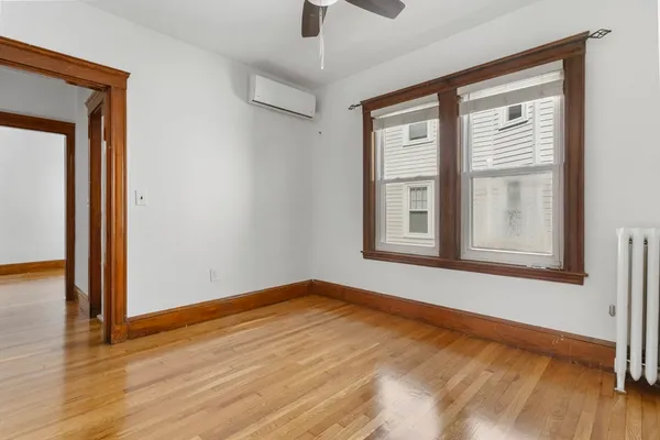 a view of an empty room with wooden floor and a window