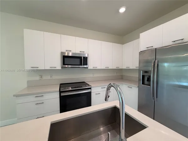 a kitchen with a refrigerator and a stove top oven