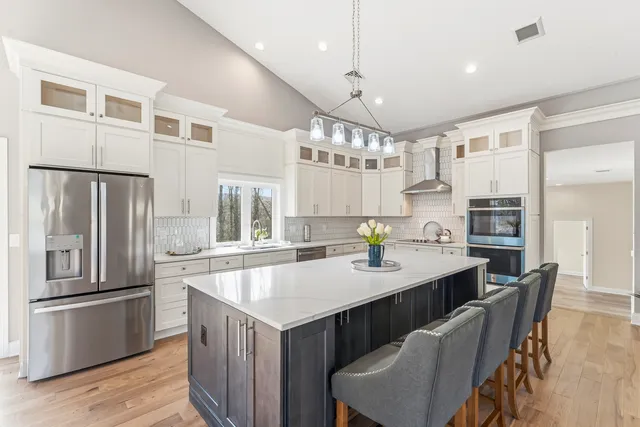 a kitchen with granite countertop a refrigerator a stove a sink dishwasher a dining table and chairs with wooden floor