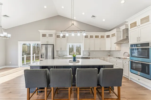 a kitchen with granite countertop a dining table chairs and white cabinets