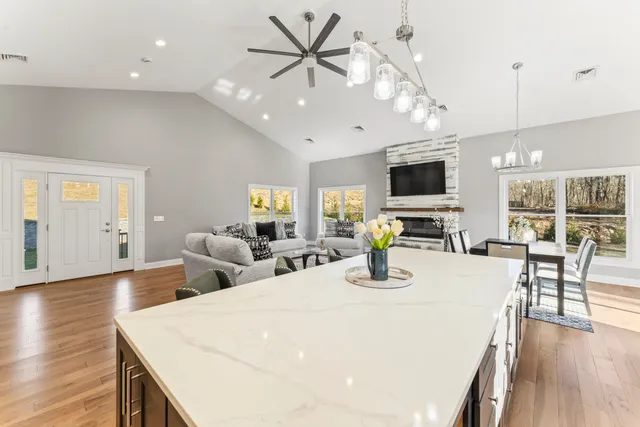 a kitchen with stainless steel appliances kitchen island granite countertop a stove a sink a dining table and chairs with wooden floor