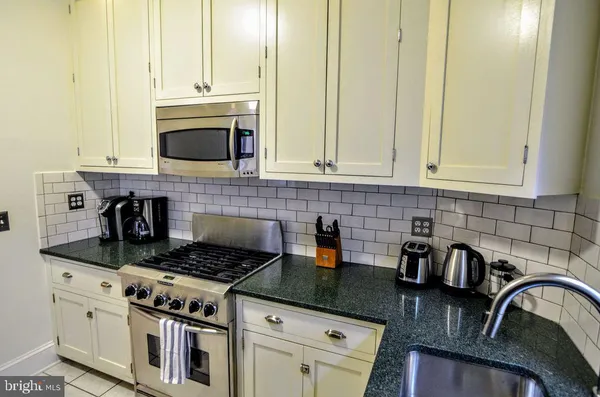 a kitchen with granite countertop a stove a sink and a white cabinets
