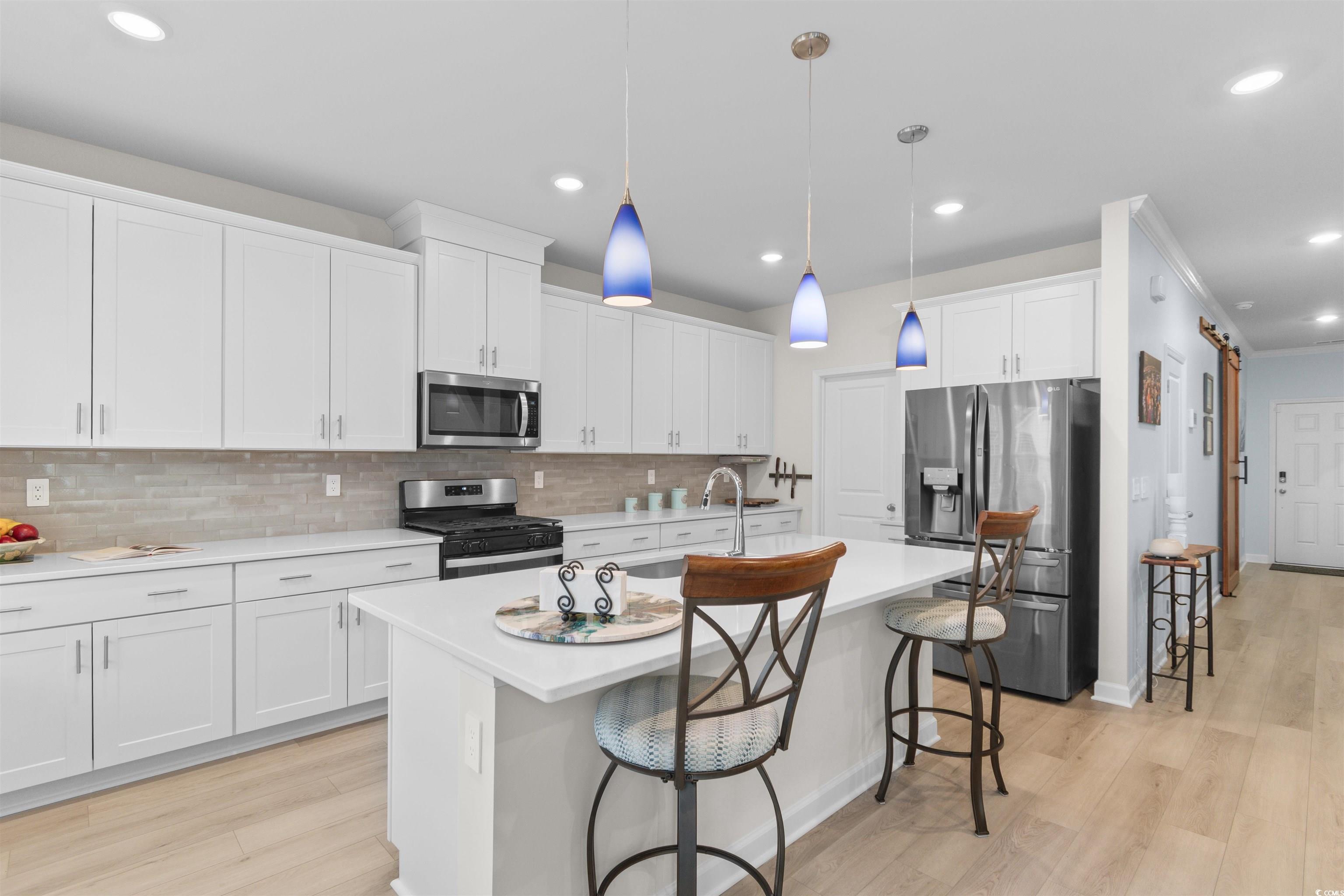 4059 Bayhill Street Myrtle Beach, SC 29579 - Photo 11 of 40 Kitchen with a breakfast bar, stainless steel appliances, decorative light fixtures, light wood-style flooring, and recessed lighting