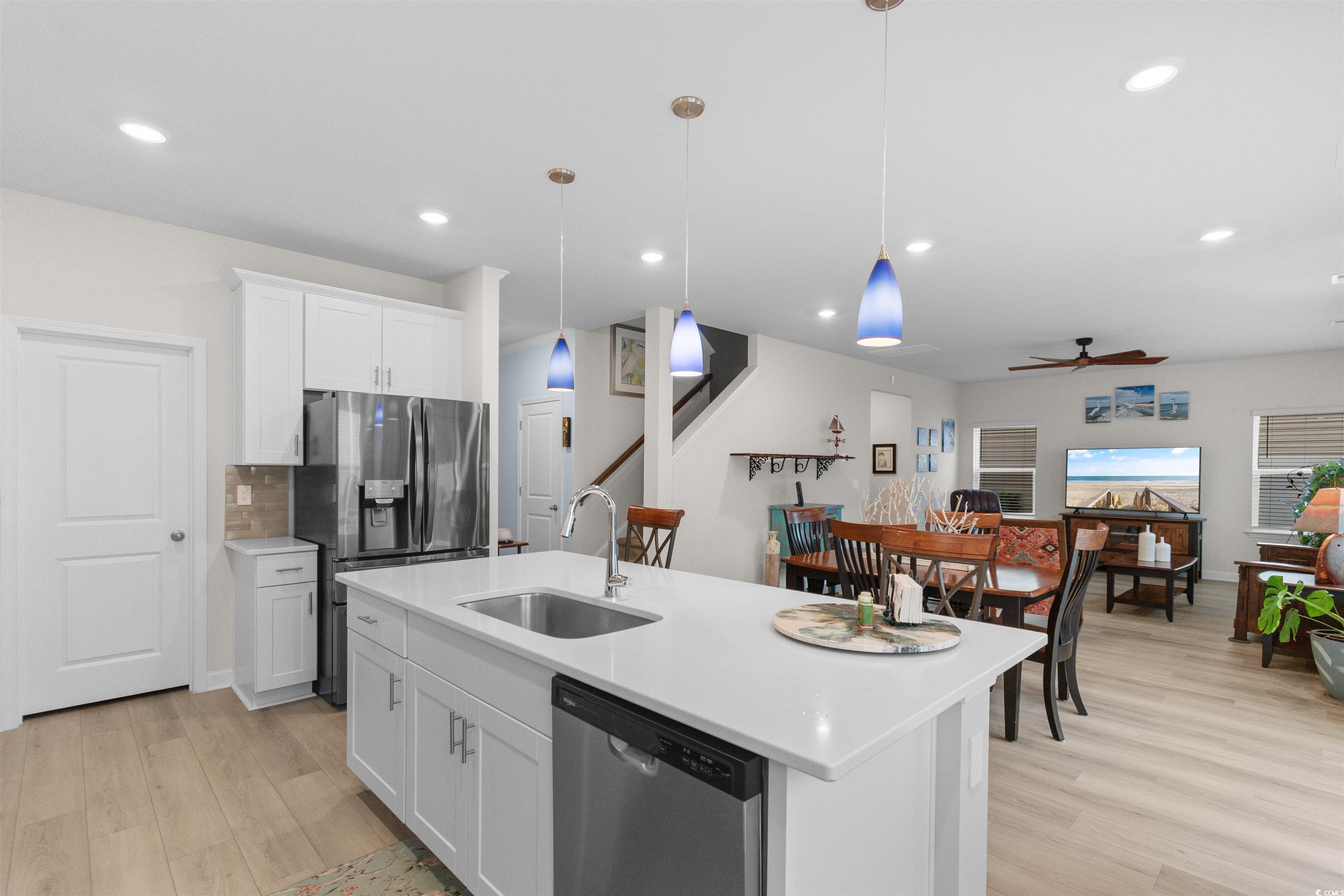 4059 Bayhill Street Myrtle Beach, SC 29579 - Photo 6 of 40 Kitchen featuring white cabinetry, stainless steel appliances, hanging light fixtures, light wood-style floors, and an island with sink