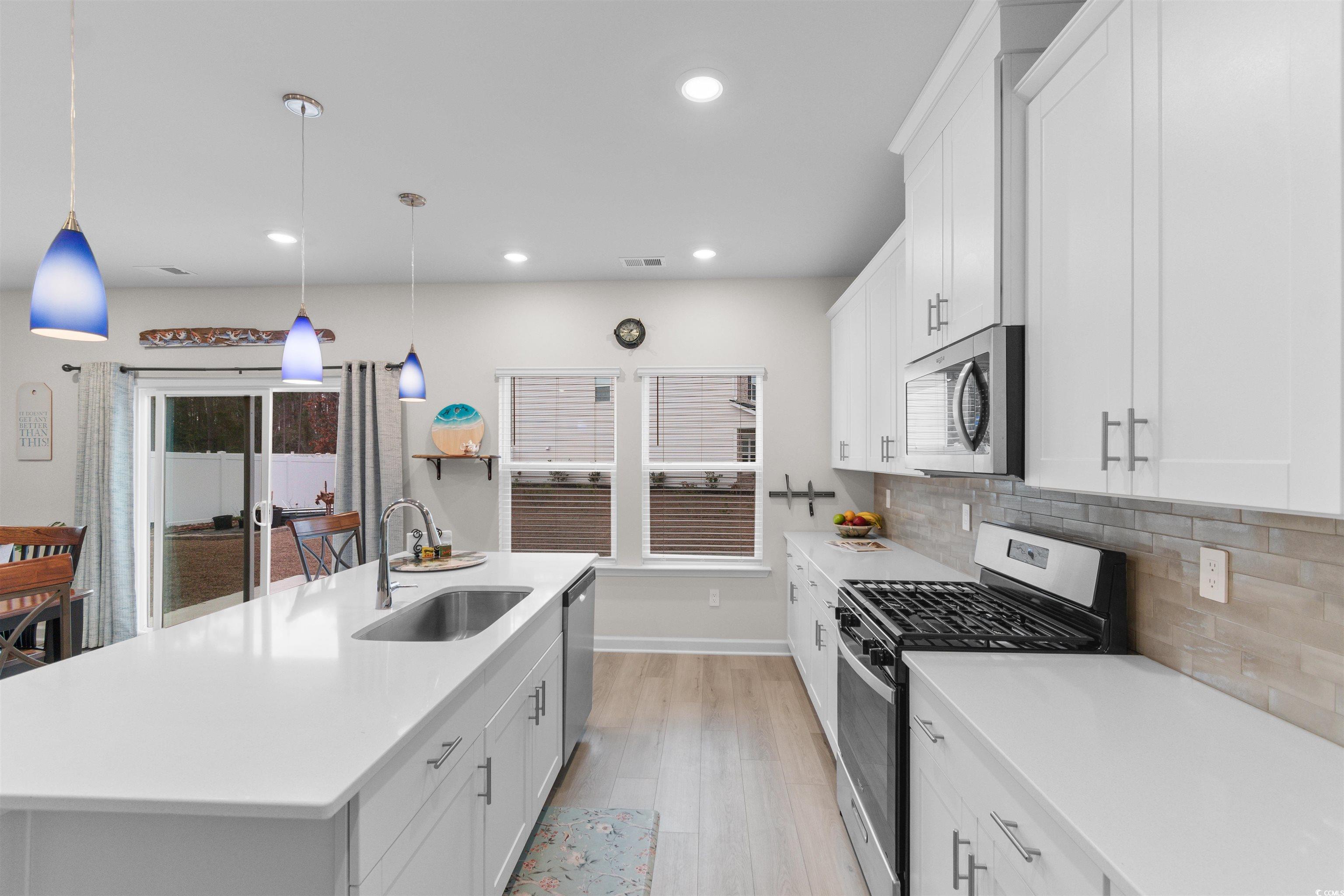 4059 Bayhill Street Myrtle Beach, SC 29579 - Photo 8 of 40 Kitchen with appliances with stainless steel finishes, white cabinets, a center island with sink, hanging light fixtures, and recessed lighting