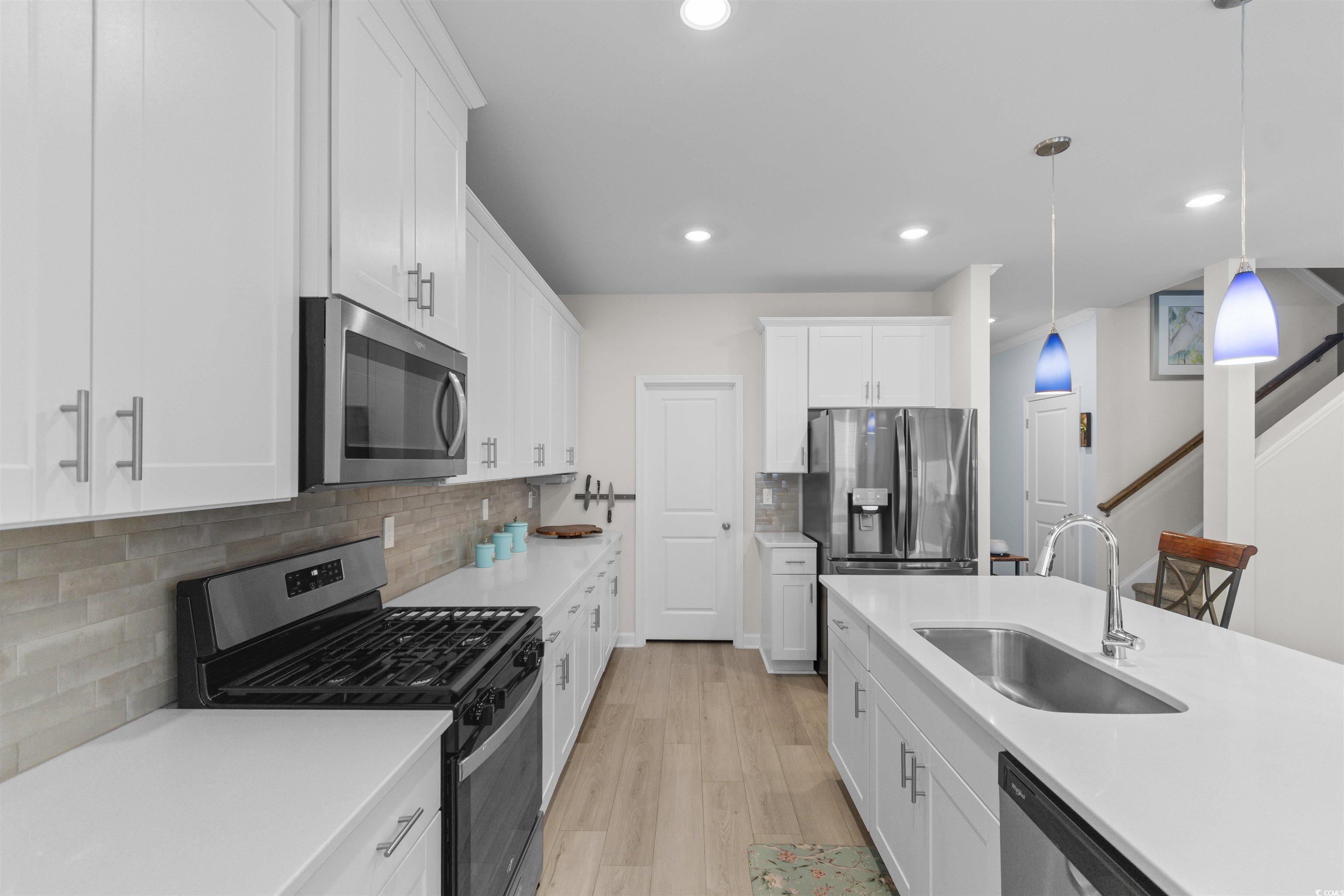 4059 Bayhill Street Myrtle Beach, SC 29579 - Photo 10 of 40 Kitchen with appliances with stainless steel finishes, white cabinets, decorative light fixtures, tasteful backsplash, and light stone counters