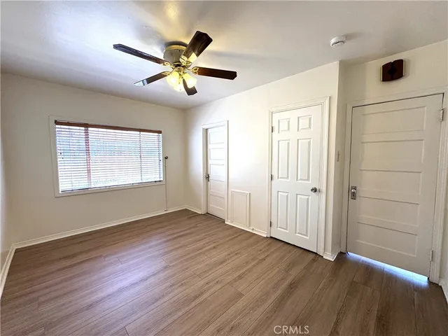 an empty room with wooden floor fan and windows