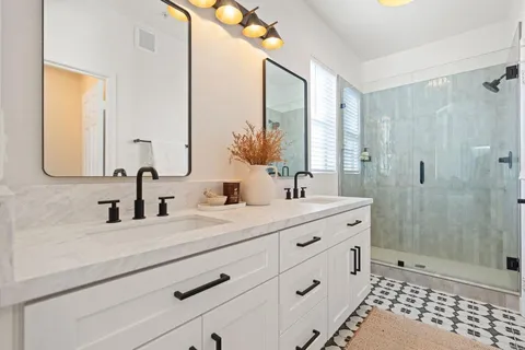 a bathroom with a double vanity sink mirror and shower