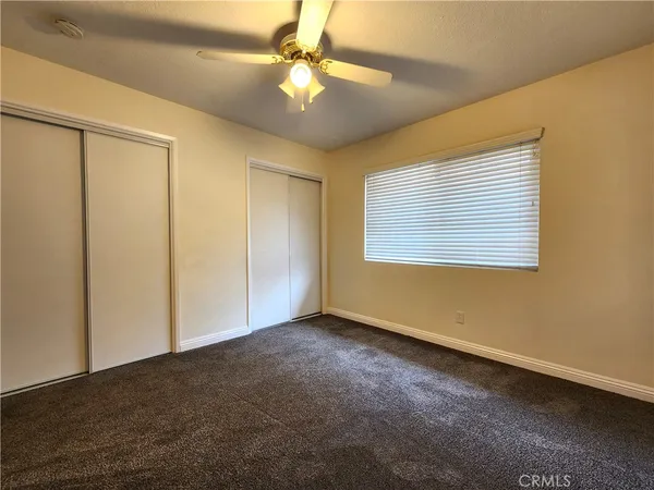 an empty room with a ceiling fan and carpet