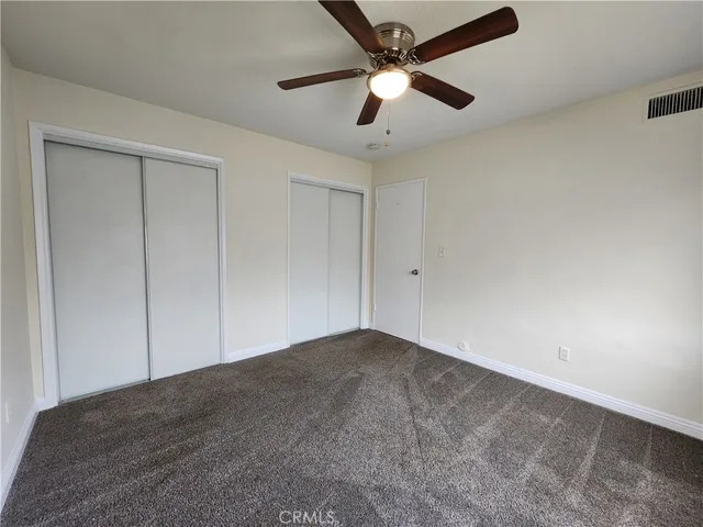 an empty room with a ceiling fan and carpet