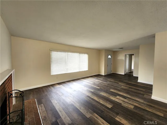 a view of an empty room and wooden floor and a window
