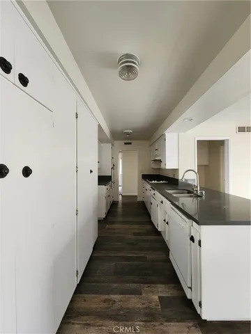a large white kitchen with wooden floor and a sink