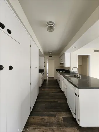 a large white kitchen with wooden floor and a sink